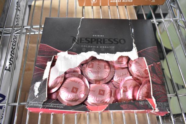 Damaged box of Nespresso Colombia Organic pods, visible pink capsules. Box reads "Origins Colombia Organic."