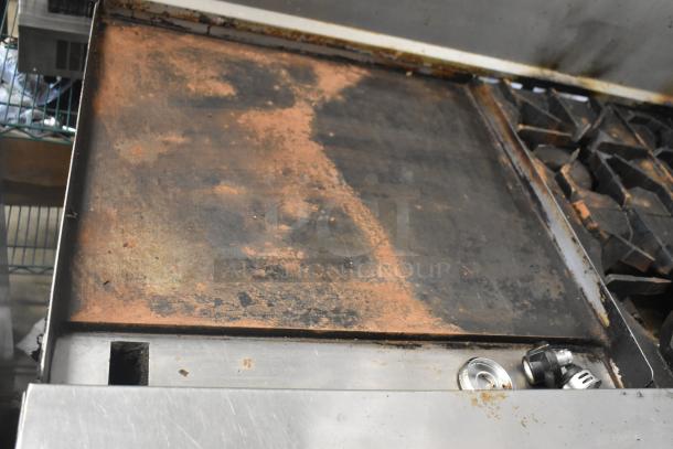 American Range commercial gas 6-burner stove, flat top griddle, dual ovens, backsplash, signs of wear.