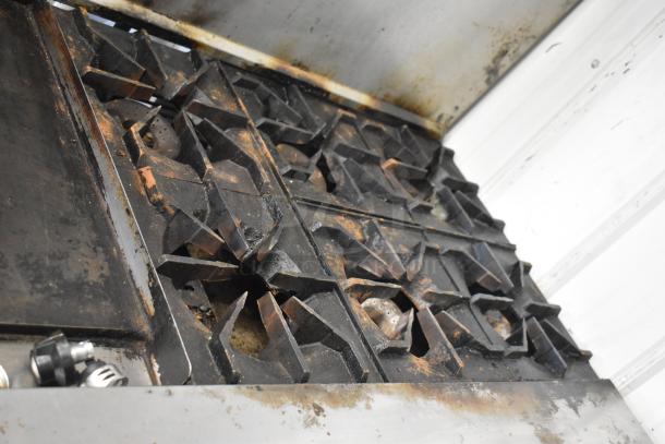 American Range 6 burner gas range with flat top griddle, dual ovens, and backsplash; visible wear and rust on burners.