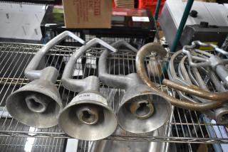 Four various dough hook attachments for Hobart mixers on a metal shelf, in used condition, with visible wear.