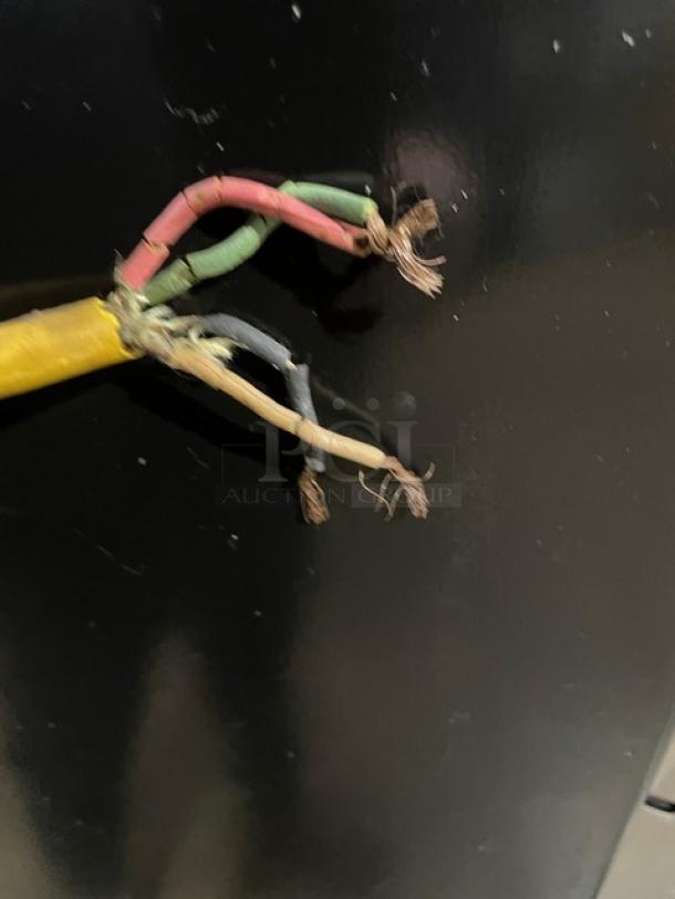 A damaged electrical cord with frayed wires against a black background.