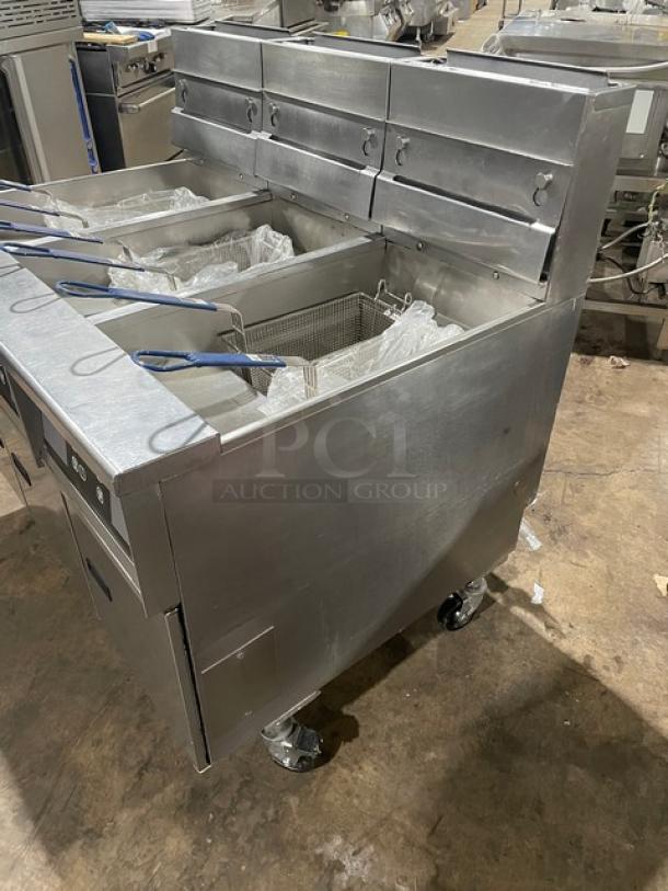 Pitco SG14JS stainless steel triple-bay deep fat fryer with digital control, backsplash, basket hanger, and casters.