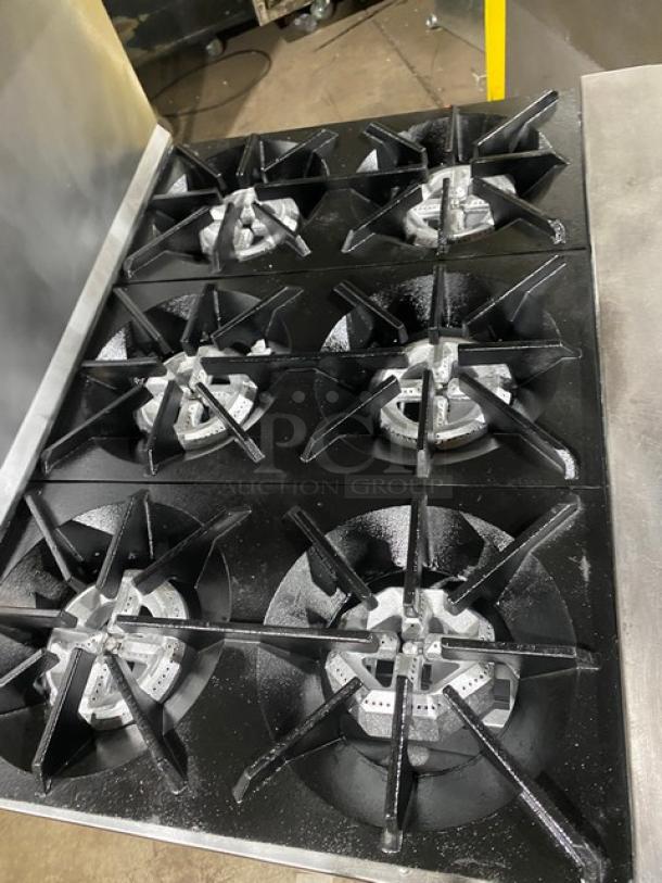 Tri-Star stainless steel gas-powered 6-burner range/oven with backsplash, overhead salamander shelf, and wired oven rack.