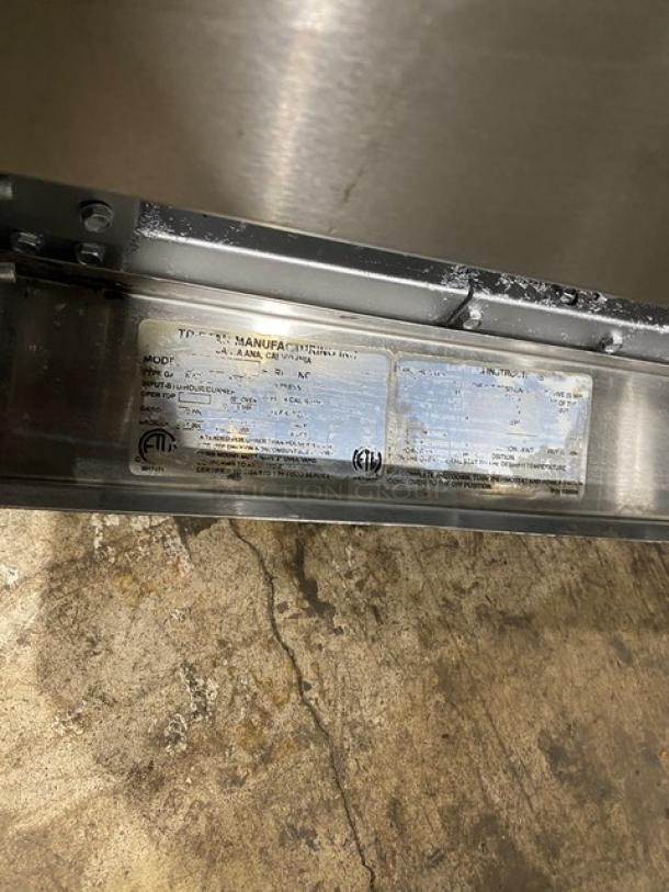 Tri-Star stainless steel gas 6-burner range/oven with backsplash, salamander shelf, wired oven rack, and label.