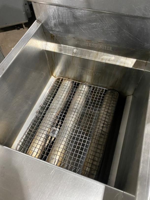 American Range commercial stainless steel gas deep fryer with backsplash, basket hanger, and fry basket; visible oil level marking.