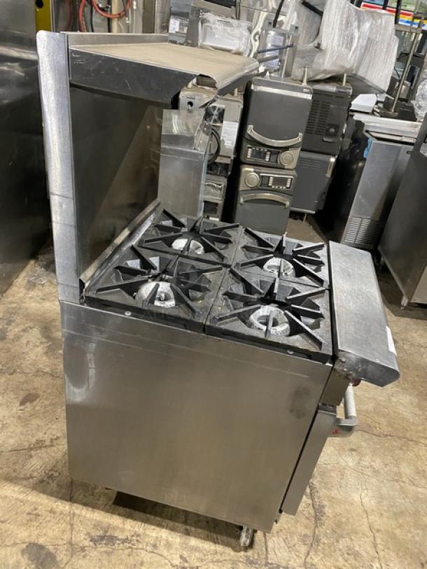 American Range stainless steel 4-burner oven combo with backsplash, overhead salamander shelf, and wired oven rack. On legs.