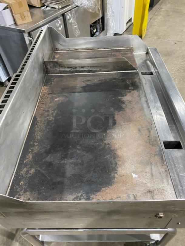 WoodStone stainless steel natural gas countertop plancha griddle with split top, back/side splash, undershelf cart, and casters. Model WSPL48364CT00NG.