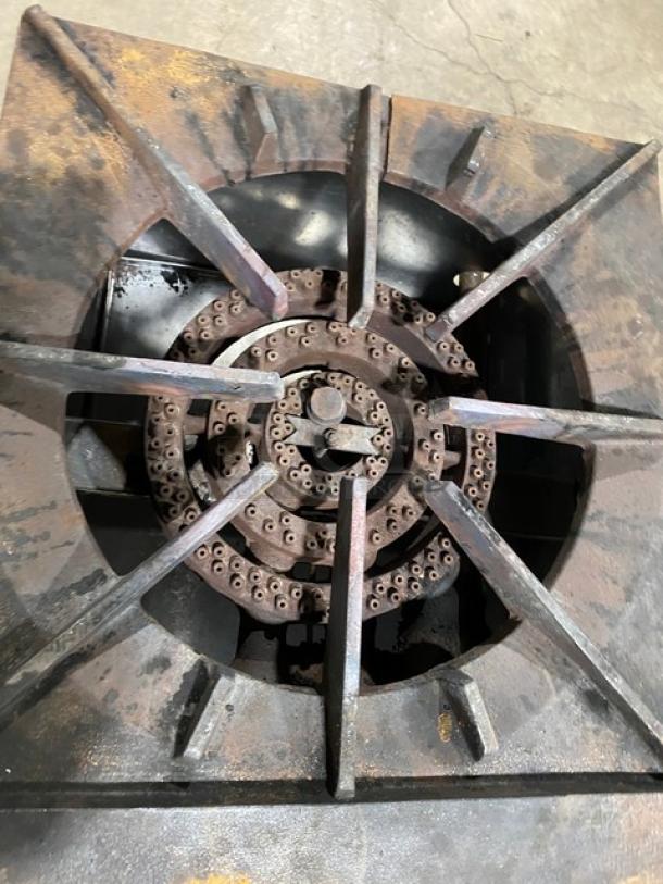 U.S. Range natural gas single burner stock pot range with sturdy grate and visible wear. Comes with casters for mobility.