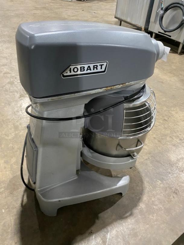 Hobart Legacy Series HL200-1STD 20 Qt. commercial mixer, gray, with stainless steel bowl guard and mixing bowl, on legs.