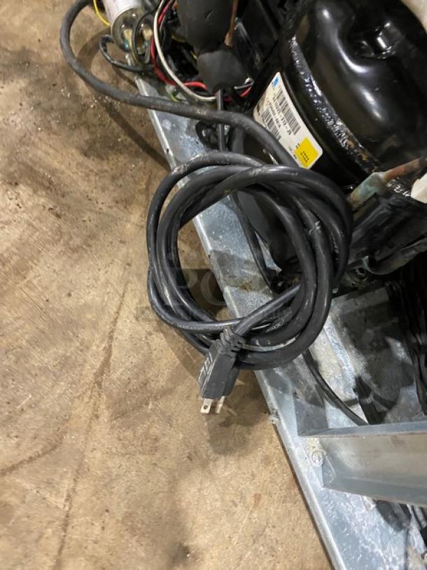 Coiled power cord and wiring for Alamo Model BBT350 barback cooler, showing plug and part of unit, on a wooden floor.