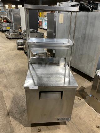 True TWT-27 commercial stainless steel single door worktop refrigerator with backsplash, double overhead shelf, poly-coated rack, on casters.