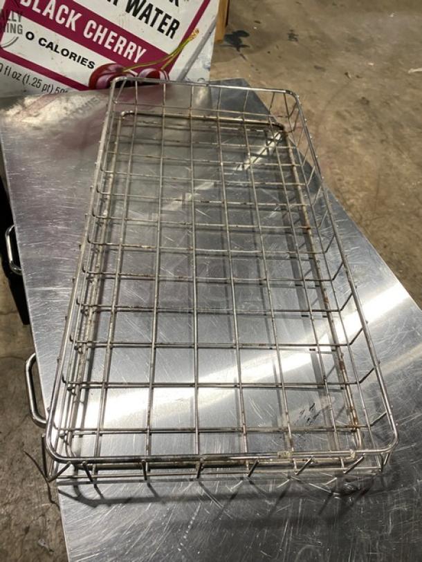 Chrome-plated full-size bagel/pastry wire rack, commercial-grade, with handles, in used condition on a metal surface.