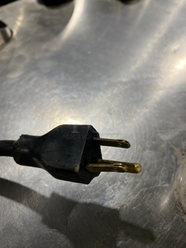 Close-up of a power plug for a Rational electric combi oven. Black, three-prong plug against a metallic background.