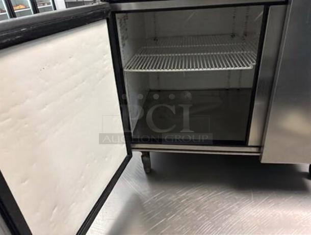 Delfield 3-door refrigerated worktop prep table, stainless steel, open door view, shelving visible, fully tested.