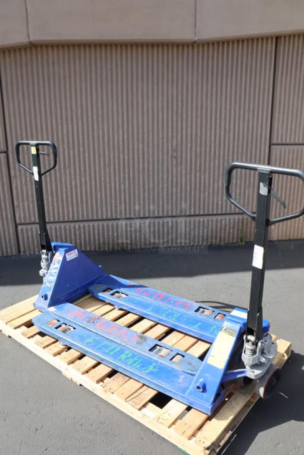 Pair of Lavex pallet jacks on a wooden pallet, blue with black handles, showing light wear, ideal for warehouse use.