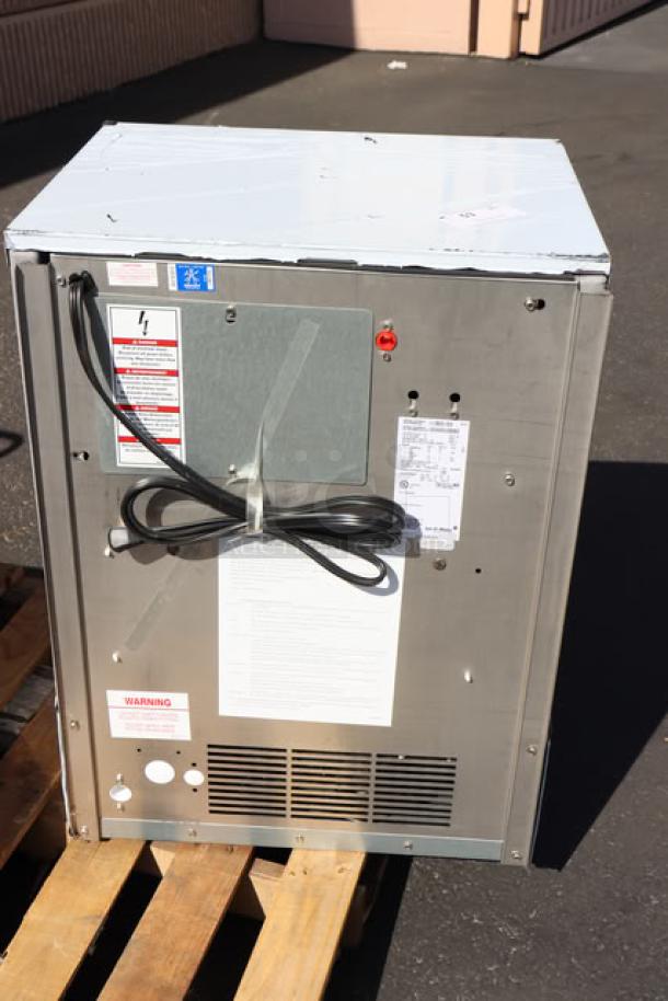 BRAND NEW Ice-O-Matic ICEU220HA air-cooled ice machine, 24.5" undercounter, 70 lb. bin, visible cables and warning label.