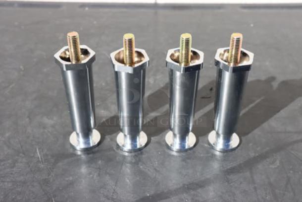 Four metal bolts with cylindrical bases and threaded ends on a dark surface.