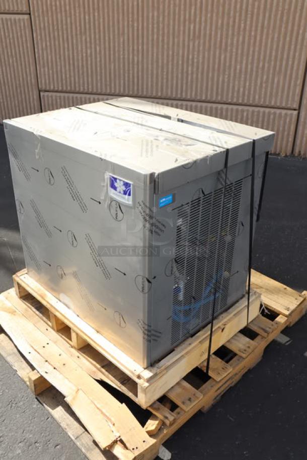 BRAND NEW SCRATCH-N-DENT Manitowoc air-cooled ice machine on pallet, protective film on surface, minor cosmetic wear.