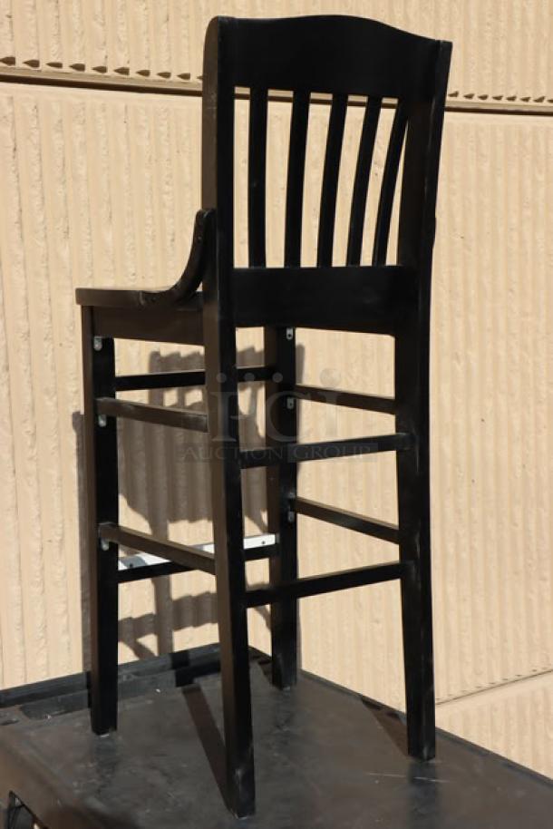 Brand new Lancaster Table & Seating bar height wooden barstool, black finish, visible scratches and dents, sturdy slatted back.