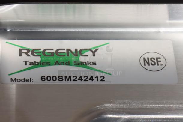 Regency stainless steel mop sink label, Model 600SM242412, NSF certified, minor dents and scratches visible.