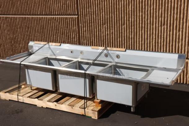 Brand new Regency 124" 16-gauge stainless steel three-compartment commercial sink with two drainboards. Model 600S32424218. Back right leg socket bent.