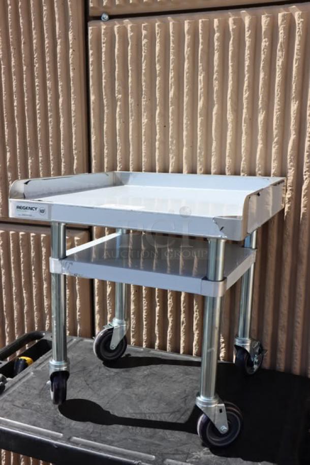 Regency 600ES2424GK 24"x24" stainless steel equipment stand with galvanized undershelf, casters, minor scratches visible.
