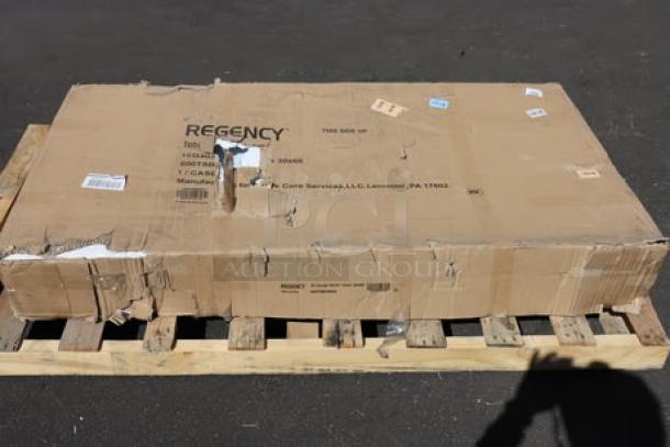 BRAND NEW Regency 600TSB3060S 30" x 60" stainless steel work table in damaged box on pallet. Model info visible.