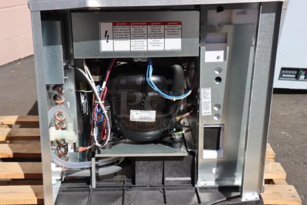 Brand new Ice-O-Matic CIM0530HA90 ice machine, showing internal components, minor cosmetic dents visible, model labels and serial number intact.