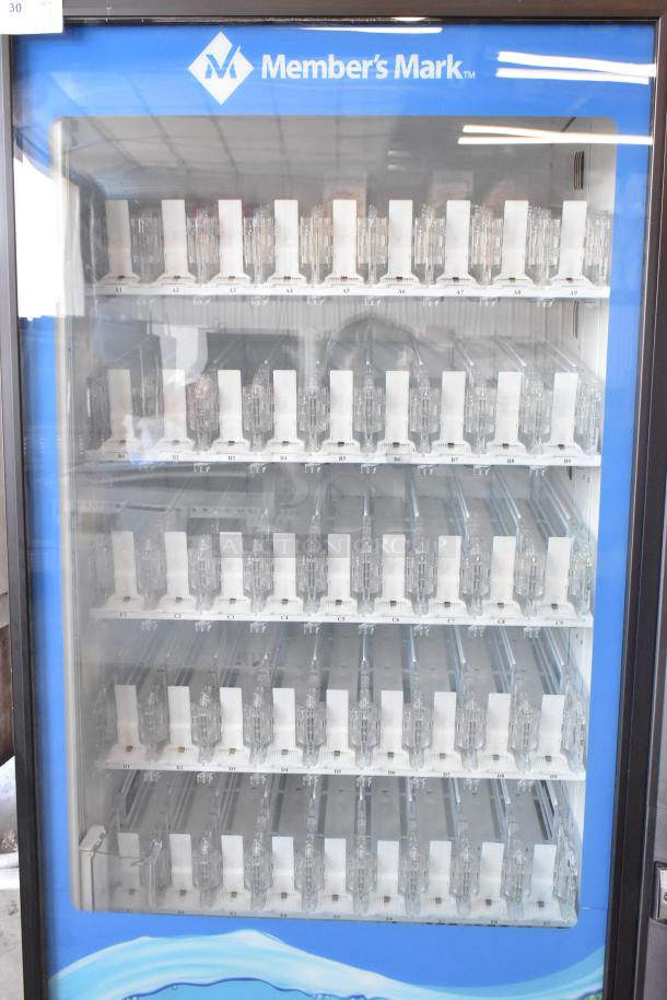 Member's Mark commercial drink vending machine with bill acceptor, glass front, empty slots, blue and black design.
