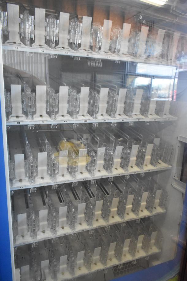 Commercial bottled drink vending machine with bill acceptor, featuring multiple empty slots and clear front panel.