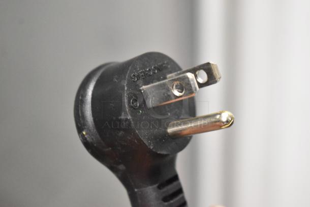 Close-up of a power plug for a True TSCI-600R-G-PH cooler, 115 volts, 1 phase. Black plastic with metal prongs.