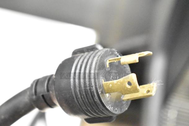 Close-up of a power plug for the Schaerer Barista Automatic 2 Group Espresso Machine, showing its prongs and black casing.