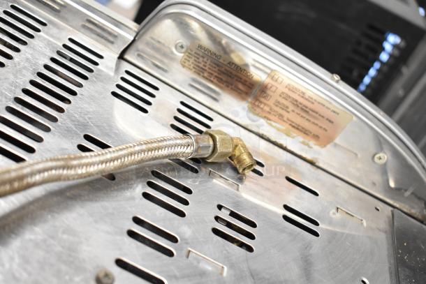 La Cimbali M29 Select espresso machine with visible metal casing, hose connection, and caution label on top surface.