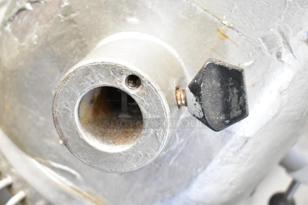 Close-up of a used commercial planetary dough mixer part, showing wear and a black adjustment knob.