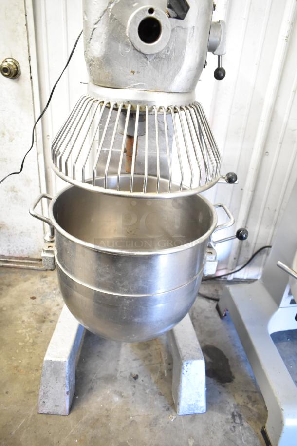 Commercial planetary dough mixer with mixing bowl and guard, shows signs of use. Ideal for bakery operations.