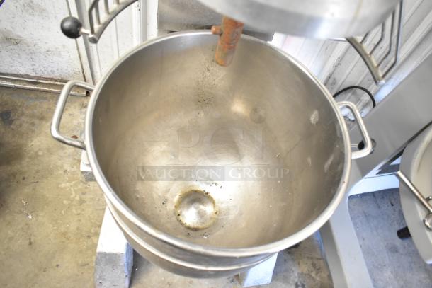 Commercial planetary dough mixer with stainless steel mixing bowl and bowl guard. Floor style, industrial use. Slight wear visible.