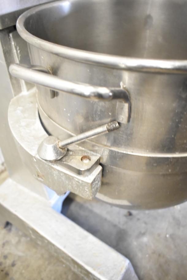 Commercial planetary dough mixer with stainless steel mixing bowl and bowl guard, showing secure attachment mechanism.