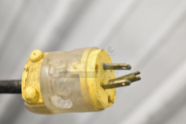 Close-up of a yellow and clear electrical plug, showing two prongs and wiring, possibly from a commercial dough mixer.