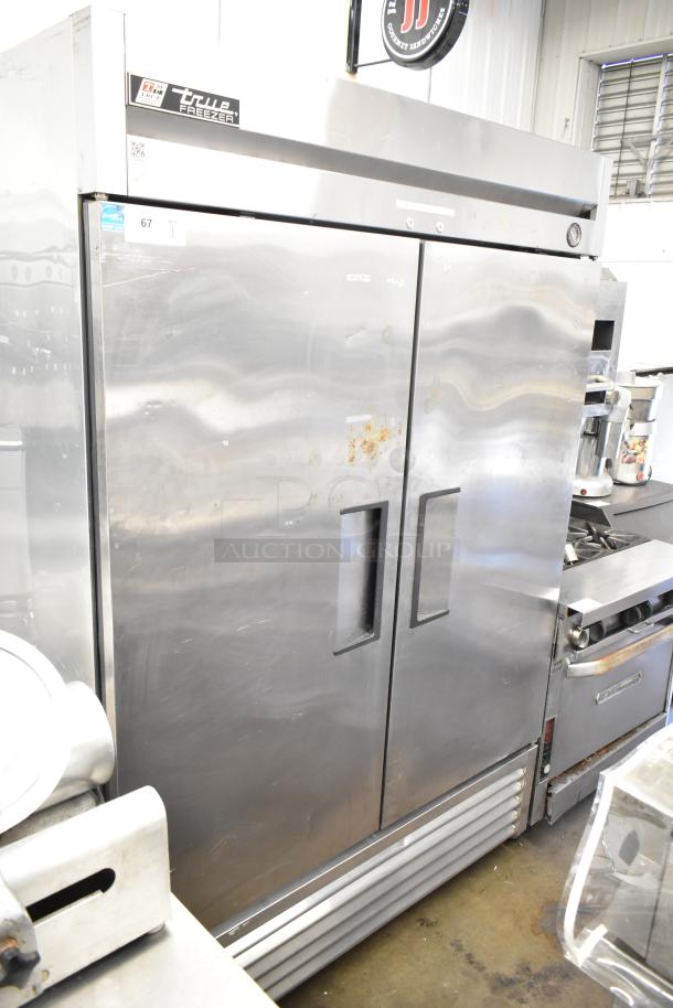 True T-49F Commercial 2 Door Reach In Freezer, stainless steel, 115 Volts, 1 Phase. Visible wear on surface, includes manufacturer logo.