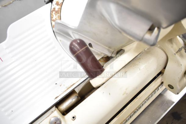 Globe 260 Commercial Meat Slicer with blade sharpener, visible wear, 115 volts, 1 phase. Sturdy handle, gravity feed.