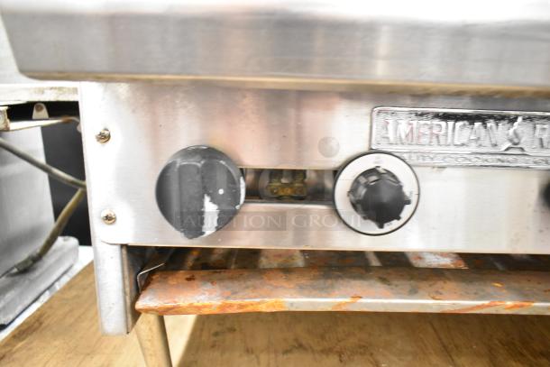 American Range commercial gas-powered 6 burner countertop stove with visible wear, control knobs, and brand label.