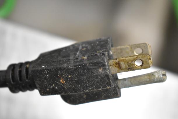 Close-up image of a worn, three-pronged electrical plug with signs of rust and grime buildup.