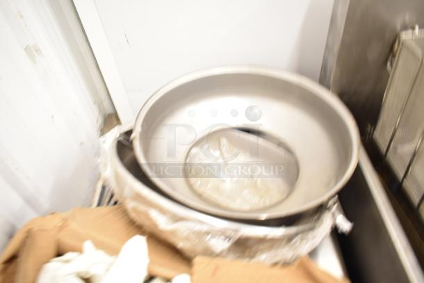 Stacked metal pizza pans, unclear condition, part of a 9-item auction lot including lightbulbs.