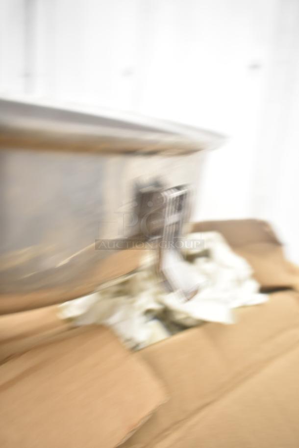 Blurry image of a metal object, possibly a pan, in a cardboard box with packaging material.