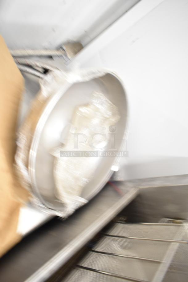 Blurry image of a metal pizza pan among various items, including lightbulbs. Items appear on a metal surface.