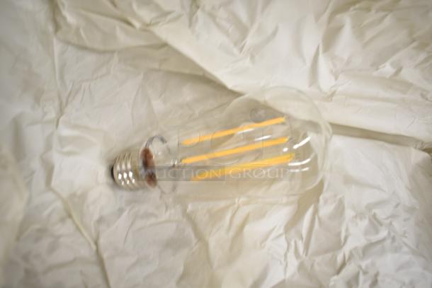 Close-up of a clear vintage-style LED bulb with filaments, resting on crumpled white paper.