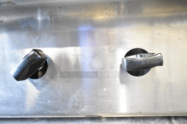 US Range Commercial Gas 8 Burner Range control knobs, stainless steel, used, visible wear, professional-grade appliance.