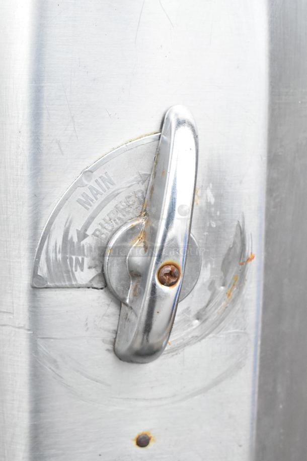 Close-up of a commercial gas-powered pizza oven's handle and indicator, showing signs of rust and wear.