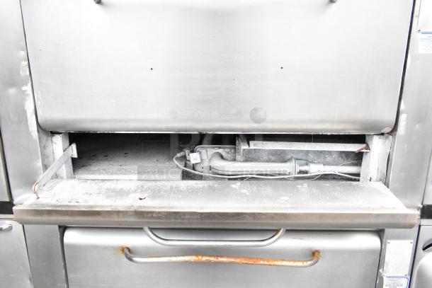 Commercial gas-powered single burner pizza oven with cooking stones. Visible wear and rust, suitable for high-volume use.