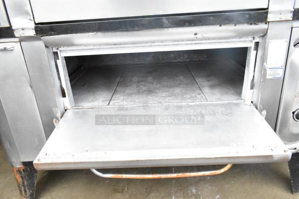 2 commercial gas-powered single burner pizza ovens with cooking stones, showing signs of wear. Auction item in used condition.